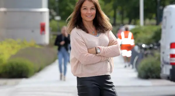 Lena Bivner, med armarna i kors, ler mot kameran utomhus.