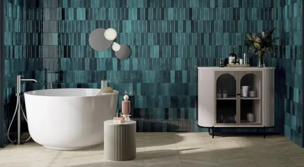 Une salle de bain moderne avec des carreaux muraux bleu sarcelle profonds, une baignoire îlot blanche et un meuble de rangement élégant. Une belle idée couleur salle de bain pour une ambiance chic.
