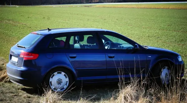 Granatowe Audi 8P na tle zielonego pola i lasu.