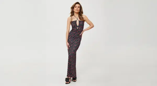 Kobieca sukienka maxi w drobne czerwone kwiatki, idealna do letnich stylizacji. Dekolt typu halter i wycięcie dodają jej charakteru.