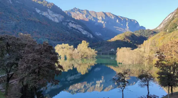 Splendido lago di Tenno in giornata, con montagne maestose e riflessi sull'acqua cristallina. Un angolo di pace autunnale.