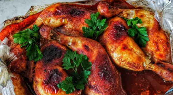 Chrupiące udka pieczone w rękawie, skąpane w aromatycznym sosie, ozdobione świeżą natką pietruszki.