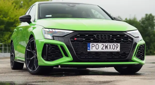 Jaskrawozielone Audi RS3 z czarnymi felgami i detalami, zaparkowane na mokrym asfalcie.