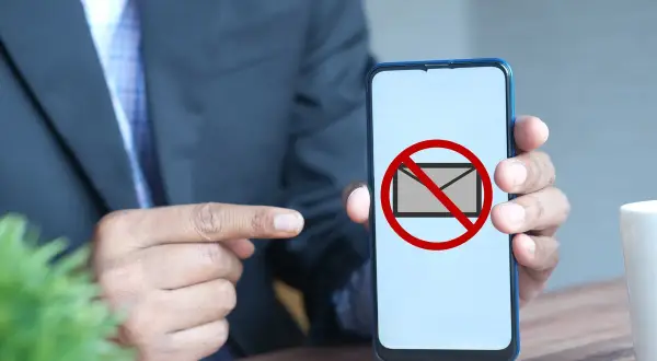 Hombre señala un teléfono con un símbolo de "no" sobre un sobre. Parece que no me llegan los sms.