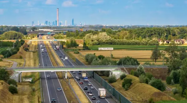 Autostrada z ruchem samochodowym i widokiem na miasto w tle.