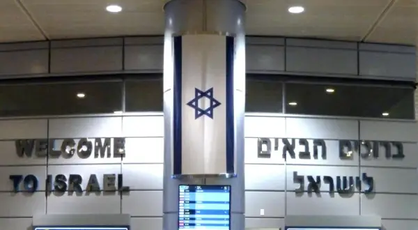 Powitanie "Welcome to Israel" i hebrajskie napisy. Flaga Izraela zwisa z kolumny. Wiza do Izraela jest ważna.