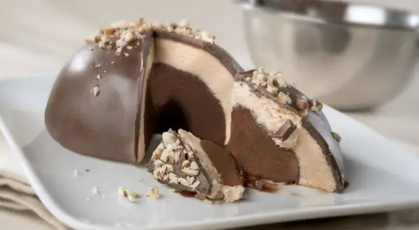 Un delizioso tartufo alla nocciola, con strati di gelato al cioccolato e crema, ricoperto di cioccolato e granella di nocciole.