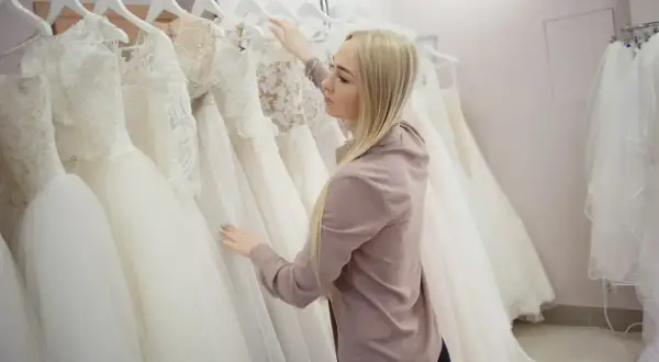 Blondynka wybiera suknię ślubną w salonie sukien ślubnych.