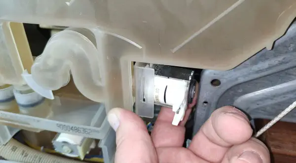 Ręka pokazuje element pompy zmywarki Bosch, który może być przyczyną błędu E22.