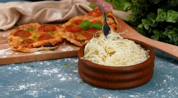 En skål med krispig pizzasallad bredvid en pizza med tomater. Perfekt tillbehör för ditt pizzasallad recept.