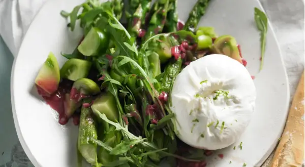 Spargel mit Burrata, grünen Tomaten und Rucola auf einem Teller. Ein köstlicher Frühlingssalat.