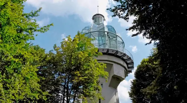 Ein Aussichtsturm mit Glaskuppel, ideal für bergische schweiz wandern. Umgeben von grünen Bäumen und blauem Himmel.
