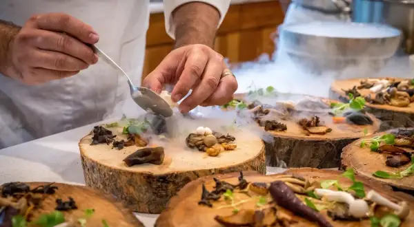 Szef kuchni serwuje danie z grzybów i ziół na drewnianych plastrach, tworząc magiczną atmosferę. To uczta godna najlepszych restauracji w Warszawie.