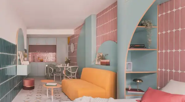 Un espacio moderno y colorido, ideal para saber como dar luz a una planta baja. Muebles curvos, estanterías y azulejos vibrantes crean un ambiente acogedor.