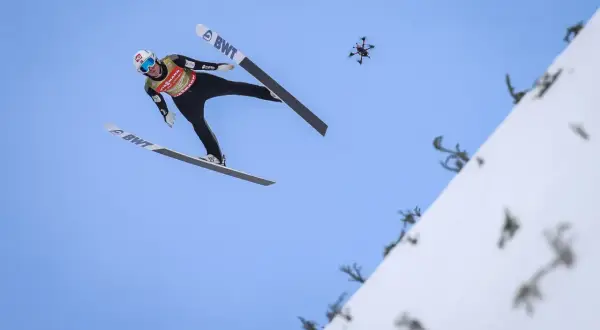 Skoczek narciarski w locie, a obok niego dron. Zastanawiasz się, ile ważą narty do skoków narciarskich?