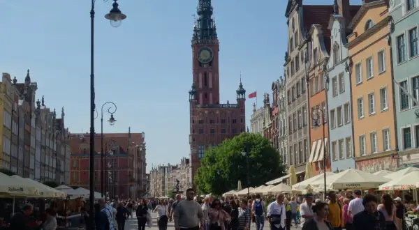 Piękna pogoda w Gdańsku w lipcu. Tłumy spacerują ulicą Długą podziwiając kamienice i Ratusz.