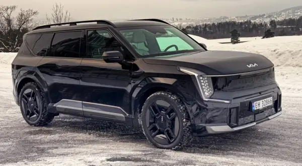 Svart Kia EV9 på en snöig väg, redo för ett vintertest. Bilen har en modern design med distinkta LED-lampor.