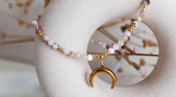 Delikatna bransoletka z kamieni, w tym opal, symbolizująca spokój i intuicję, z zawieszką w kształcie złotego księżyca.