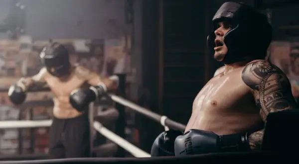 Two boxers in a ring, one leaning on the ropes, sweat glistening. This intense roadwork boxing session shows the grit and determination of the fighters.