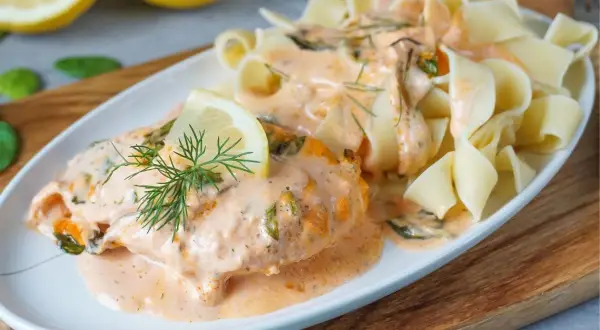 Zartes Lachsfilet in cremiger Sahnesauce mit Dill und Zitrone, serviert mit breiten Bandnudeln. Ein köstliches Lachs Sahne Gratin.
