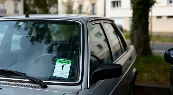 Autocollant vert sur le pare-brise d'une voiture indiquant "Contrôle technique périmé 1 mois".