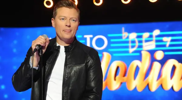 Artysta z wyciągniętym językiem trzyma mikrofon na tle napisu "Jaka to melodia". Czyżby zapowiadał największe zmiany w regulaminie?