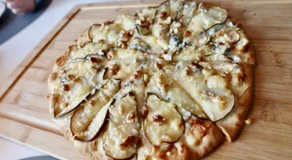 En utsökt pizza med päron, valnötter och krämig gorgonzola på en träskärbräda.