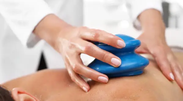Dłoń terapeuty wykonuje masaż bańką chińską, ukazując jego relaksujące efekty na skórze.