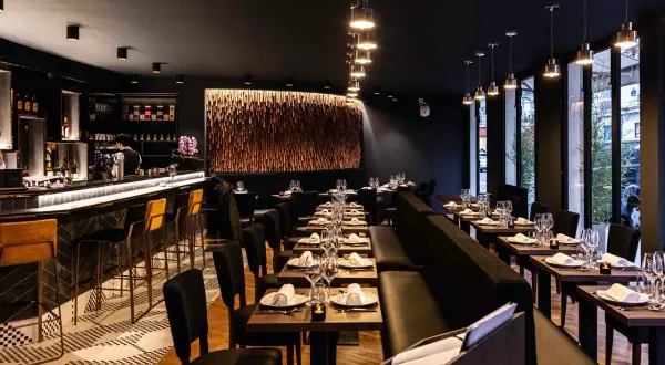 Ambiance chic d'un restaurant avec un bar lumineux, des tables dressées et une décoration murale en bois. Un endroit parfait pour un dîner en tête-à-tête, un moom mam.