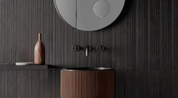 Bagno moderno con lavabo in legno scanalato, rubinetteria in metallo scuro e specchio rotondo. Parete con un suggestivo effetto bambù.
