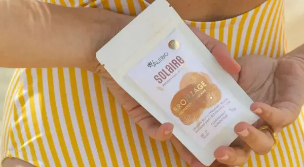 Une main tient un paquet de "Solaire Bronzage" de Valebio, suggérant une peau protégée et hâlée.