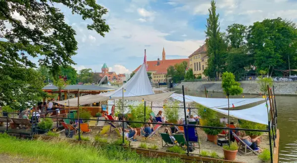 Entspannte Atmosphäre an einem Flussufer-Café in Breslau. Ein perfekter Ort für Breslau Geheimtipps, mit Liegestühlen und Sonnensegeln.