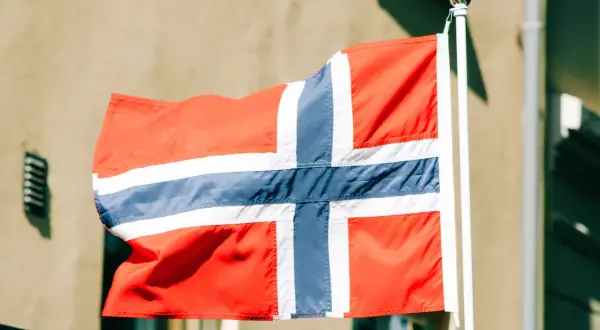 Norweska flaga powiewa na wietrze. Zastanawiasz się, ile zarabia programista w Norwegii?