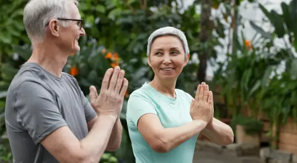 Ett äldre par ler och gör yoga utomhus. De visar att man kan leva med en lunga och njuta av livet.