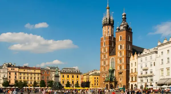 Rynek Główny w Krakowie tętni życiem. W tle Bazylika Mariacka i kolorowe kamienice.