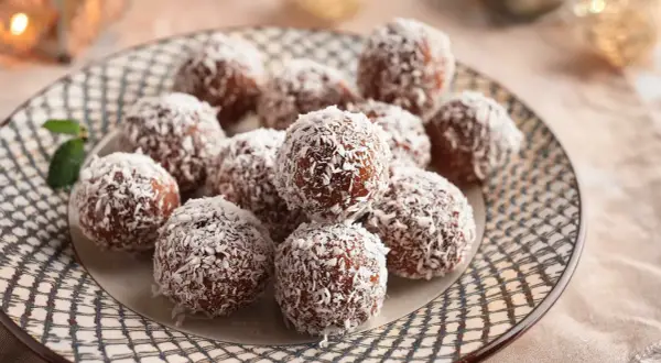 En tallrik med chokladbollar täckta av kokosflingor, redo att avnjutas. Ett enkelt chokladbollar recept för fika.