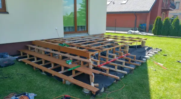 Budowa tarasu na słupach betonowych. Drewniana konstrukcja czeka na deski.