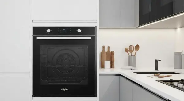 Four rosieres erreur 15 : un four encastré noir dans une cuisine moderne. Des ustensiles en bois sur le plan de travail.