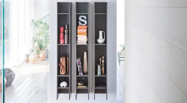 Scaffali grigi con oggetti decorativi, piante e libri, che creano un effetto camino ventilazione naturale.