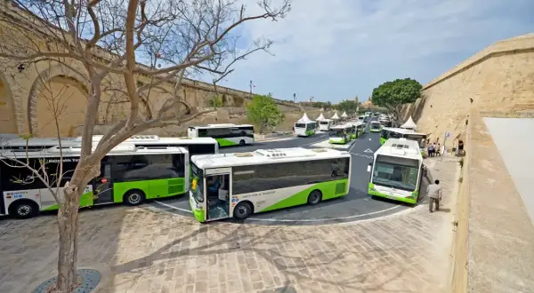 Malta autobusy z lotniska czekają na pasażerów przy zabytkowych murach.