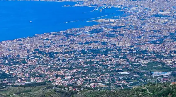 Blick über die weitläufige Stadt Neapel, Italien, mit dem blauen Meer und dem Hafen im Hintergrund.
