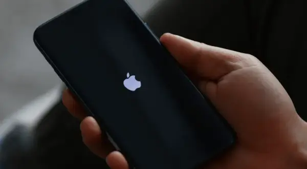 Dłoń trzyma iPhone 13 z logo Apple. Czas na reset? Dowiedz się, jak zresetować iPhone 13.