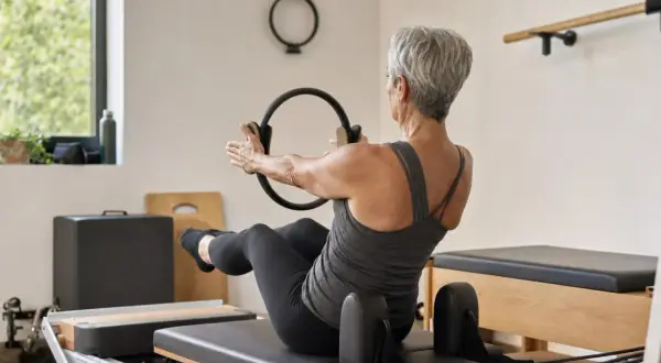 Donna matura con un anello Pilates, impegnata in un allenamento per raddrizzare la schiena a 50 anni.