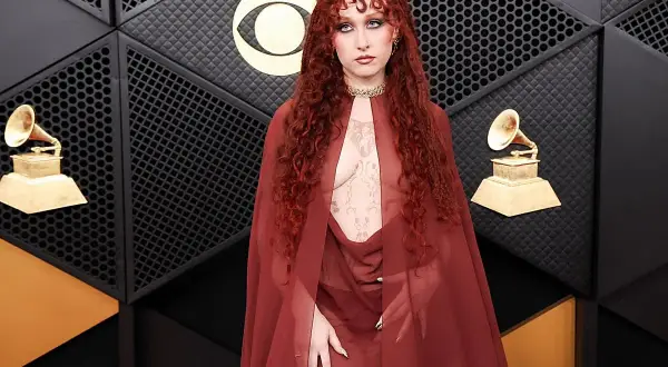 Chappell Roan, con su cabello rojo rizado y un atuendo transparente, posa en la alfombra de los Grammy.