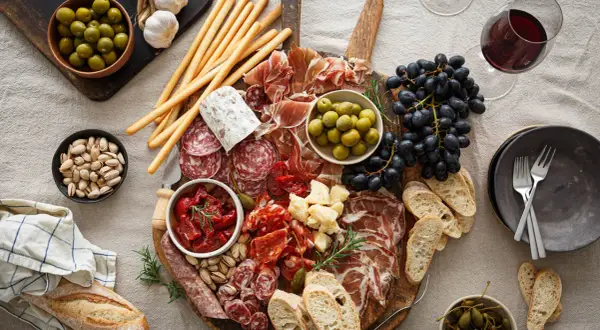 En generös bricka med italienska snacks: charkuterier, oliver, soltorkade tomater, ost, vindruvor, grissini och bröd. Perfekt för en mysig kväll.