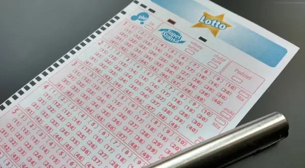 Kupon Lotto z zaznaczonymi polami do wyboru liczb i długopisem.