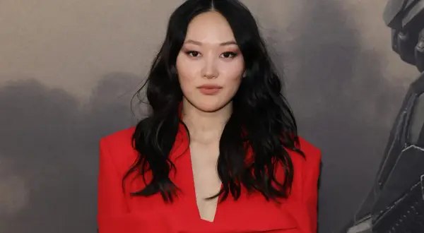 Yerin Ha, con su cabello oscuro y un elegante traje rojo, posa con confianza.