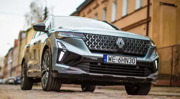 Nowy Renault Espace 2024 z charakterystycznym grillem i nowoczesnymi światłami LED, zaparkowany na brukowanej ulicy.