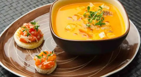 Ein cremiges Gazpacho-Rezept mit Croutons und frischen Kräutern, serviert mit kleinen Bruschettas.