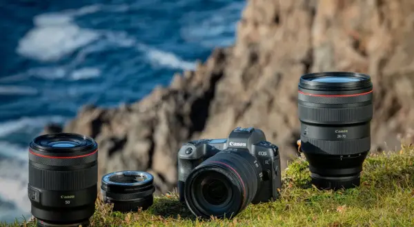 Canon EOS R camera with RF 50mm, RF 24-105mm lenses, and mount adapter on grass.